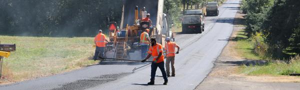 Workers paving a road on a summer day.