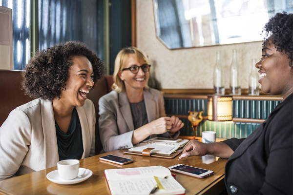 Three ladies sitting at a table for a meeting.