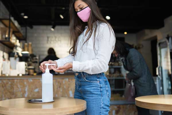 Woman using hand sanitizer at local business