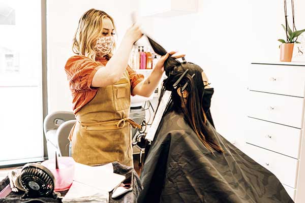 Woman getting her hair cut while wearing a face covering