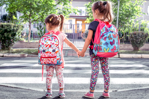 Young girls with backpacks holding hands