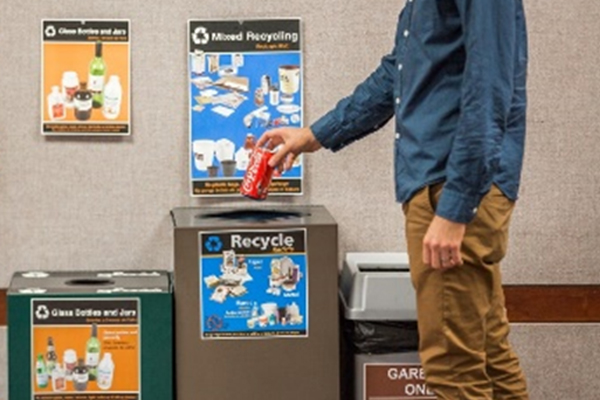 Person putting soda can in recycling bin