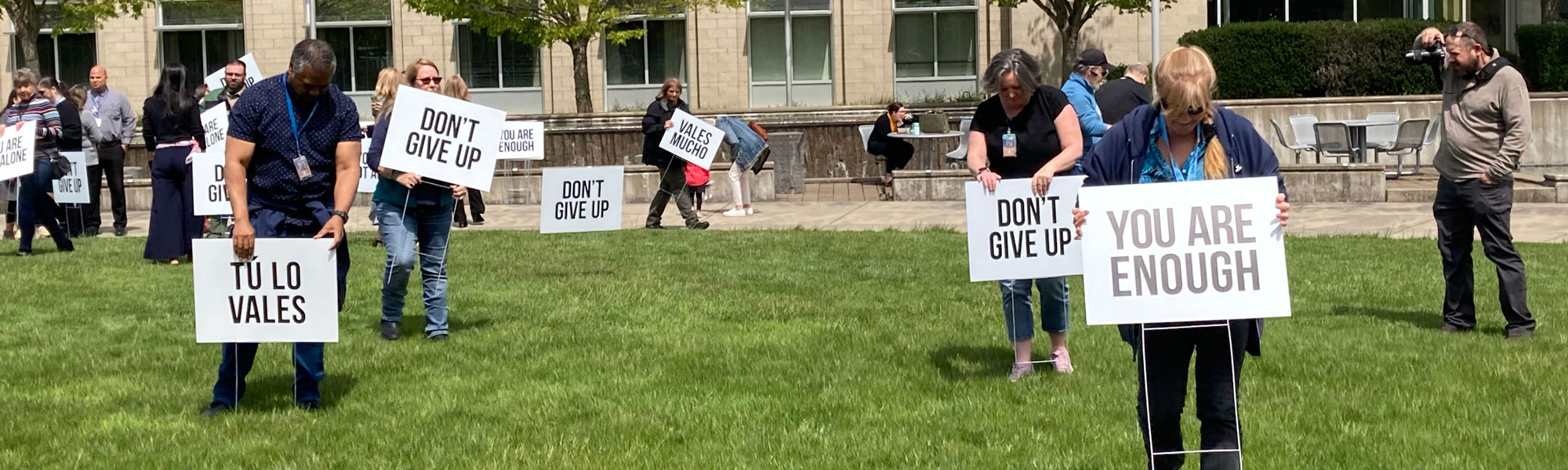 People placing signs with hopeful messages into the grass at the Circle of Honor