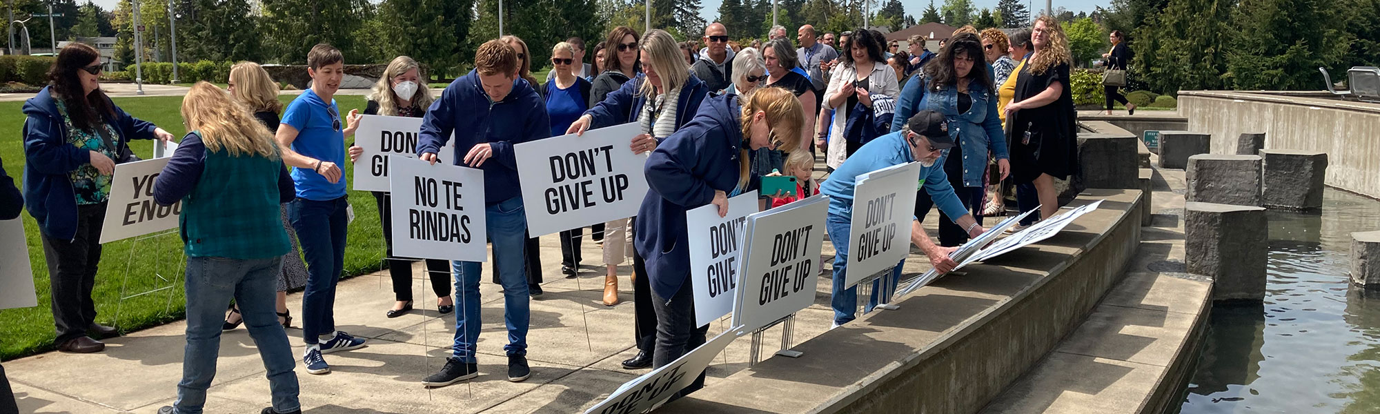 People placing signs with hopeful messages into the grass at the Circle of Honor