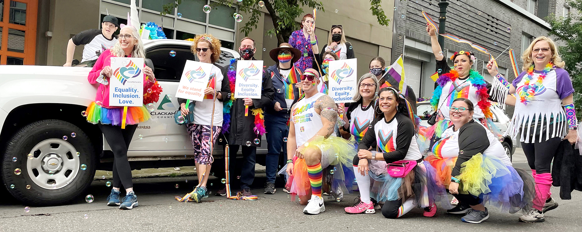 People standing in front of a ClackCo car in the pride parade