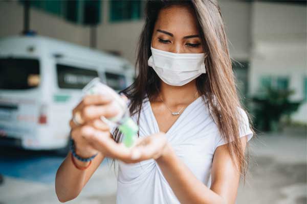 Woman with a mask using hand sanitizer