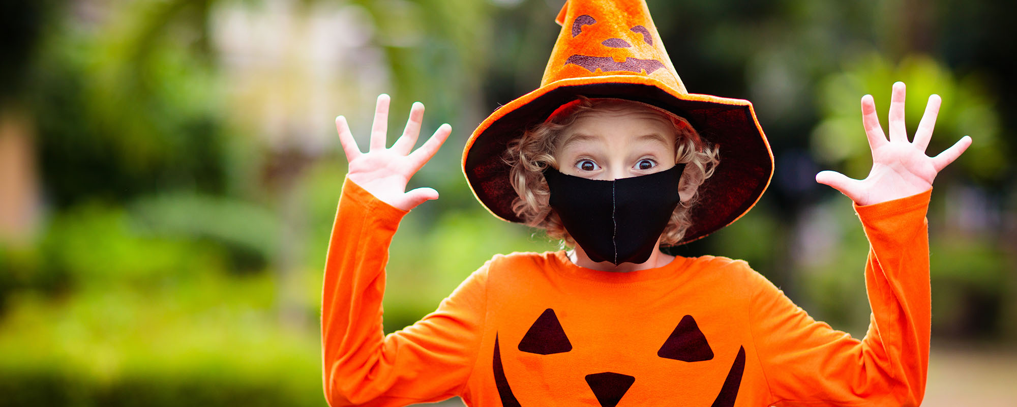 Child wearing a jack-o-lantern shirt and witch hat