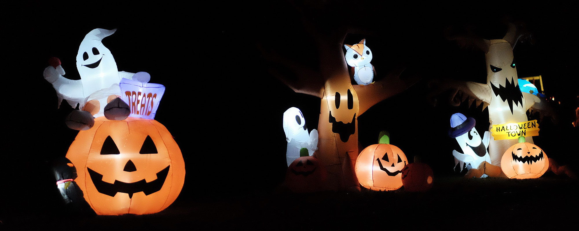 Blow up Halloween decorations of ghosts and pumpkins at night