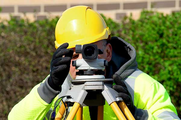 worker with hard hat looking through camera