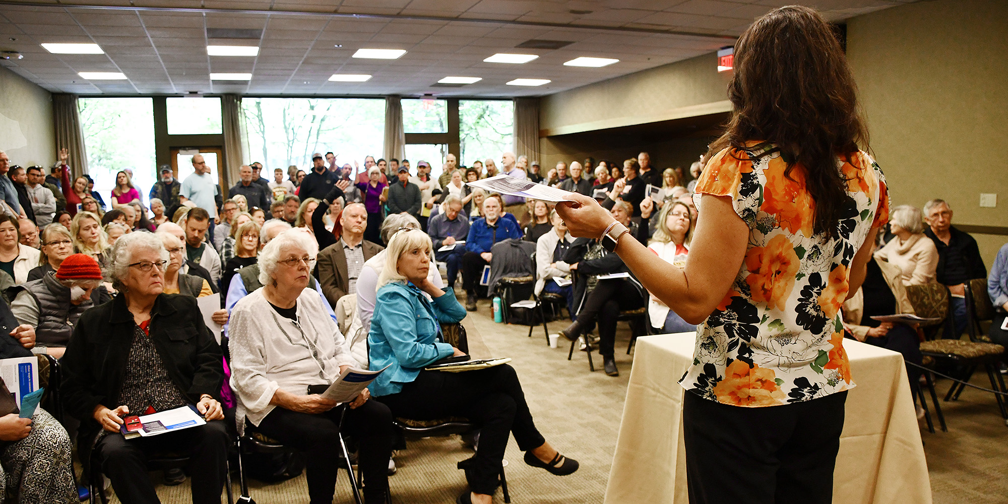 A room of people gather to hear a presentation