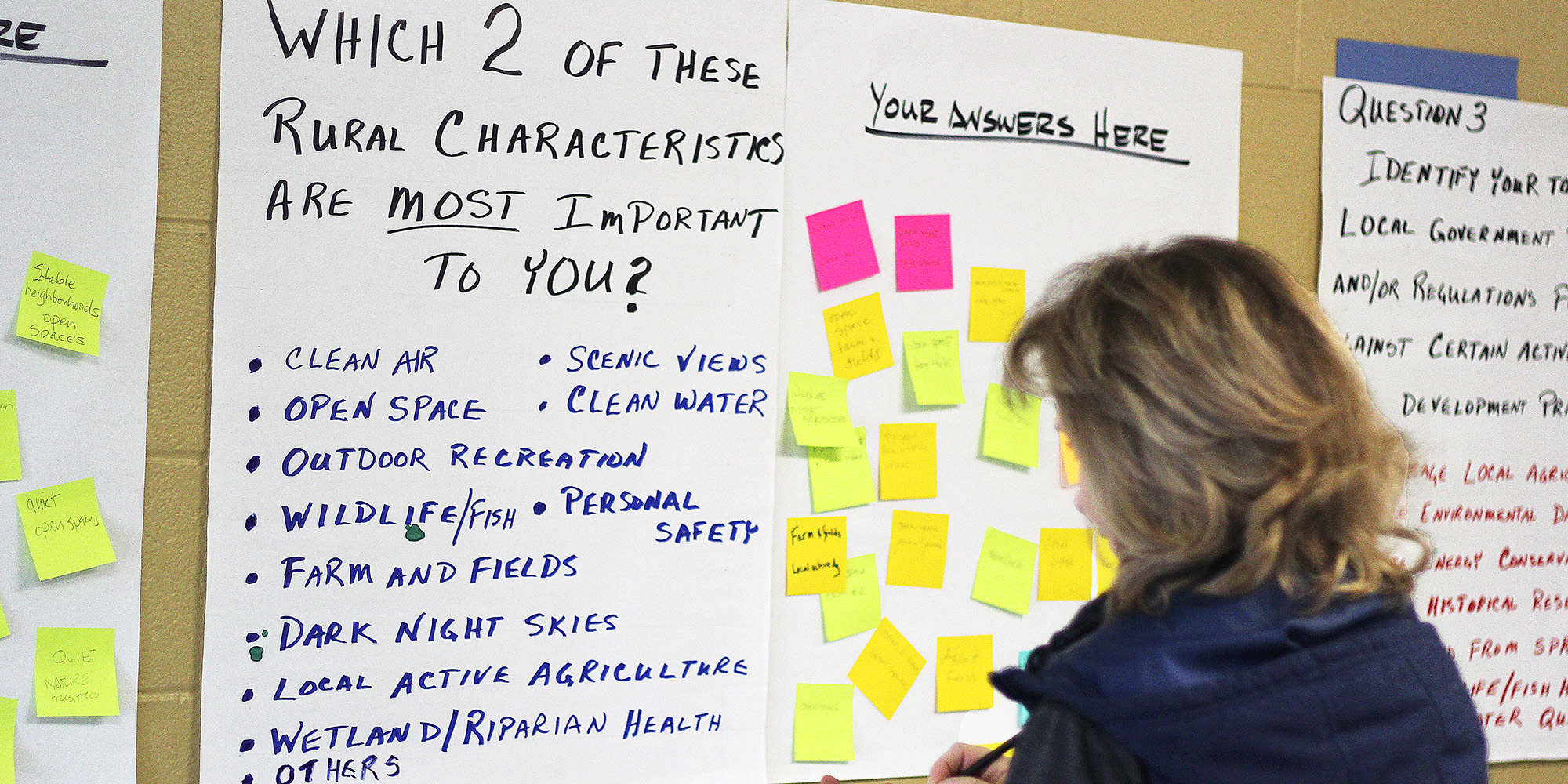 A woman reads post it notes about rural characteristics