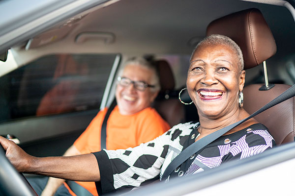 Portrait of senior woman driving a car and a friend on the passenger seat