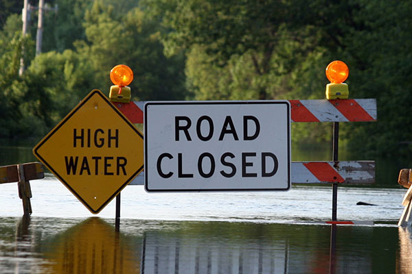 road covered with water and closure signs