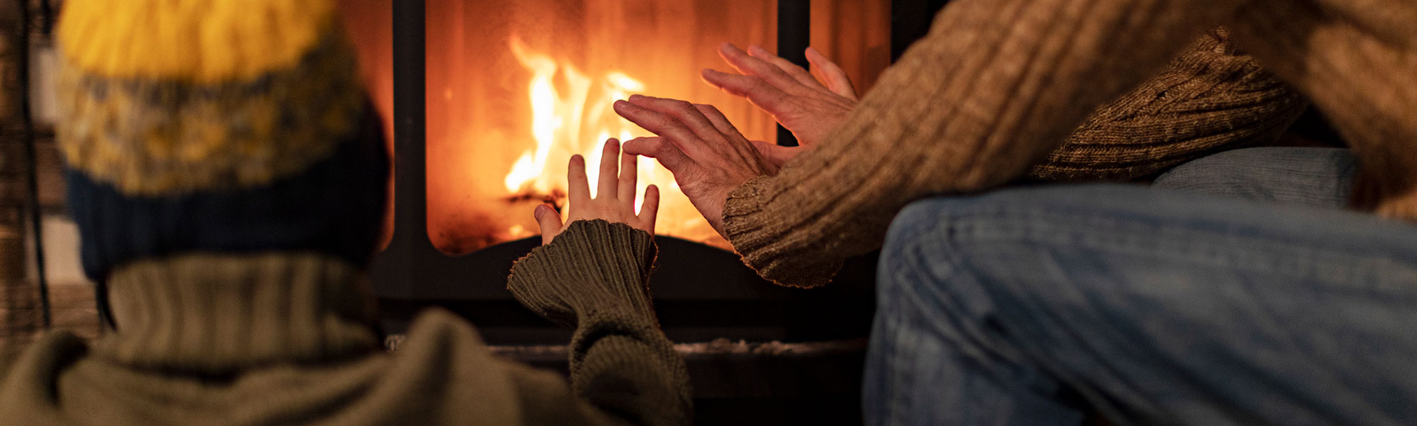 Two people warming their hands in front of a fireplace