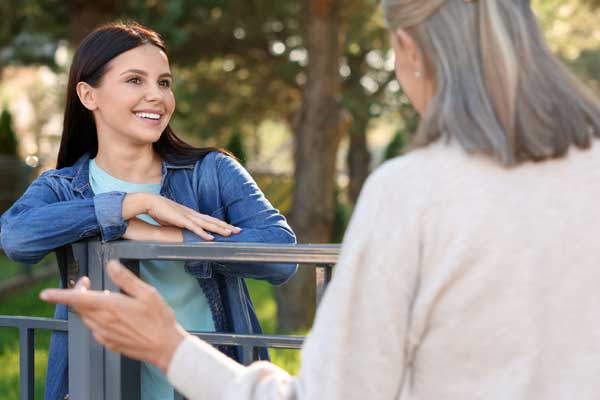 Two women talking over a fence