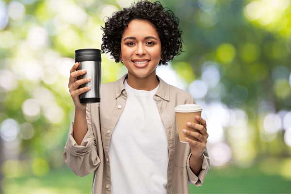 Woman holding up reusable coffee cup