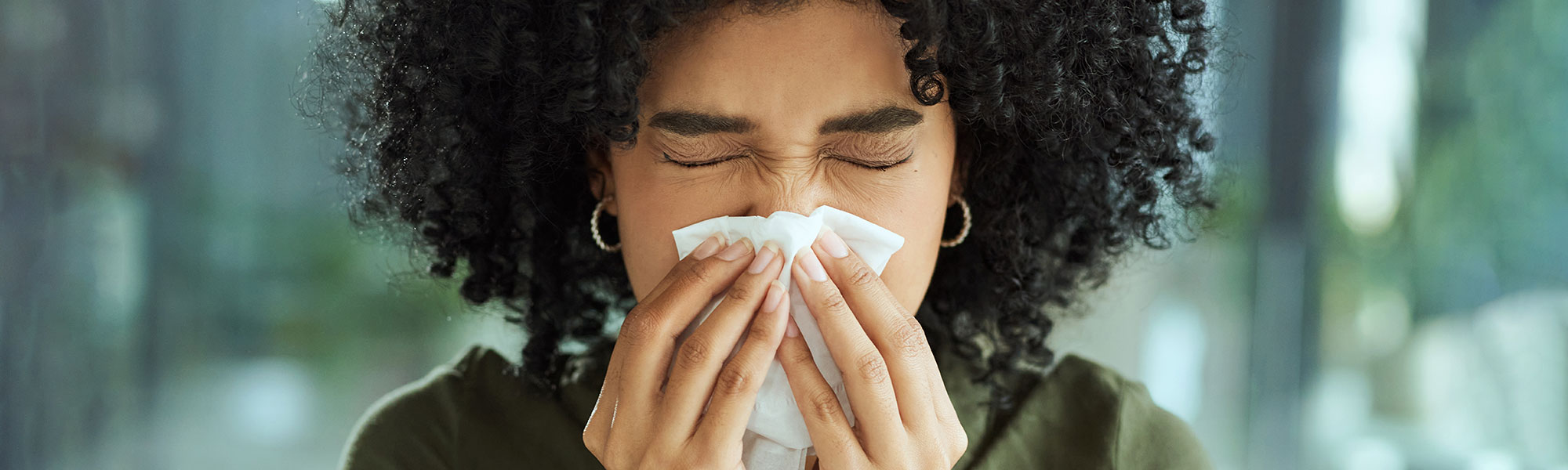 Person sneezing with tissue over their face