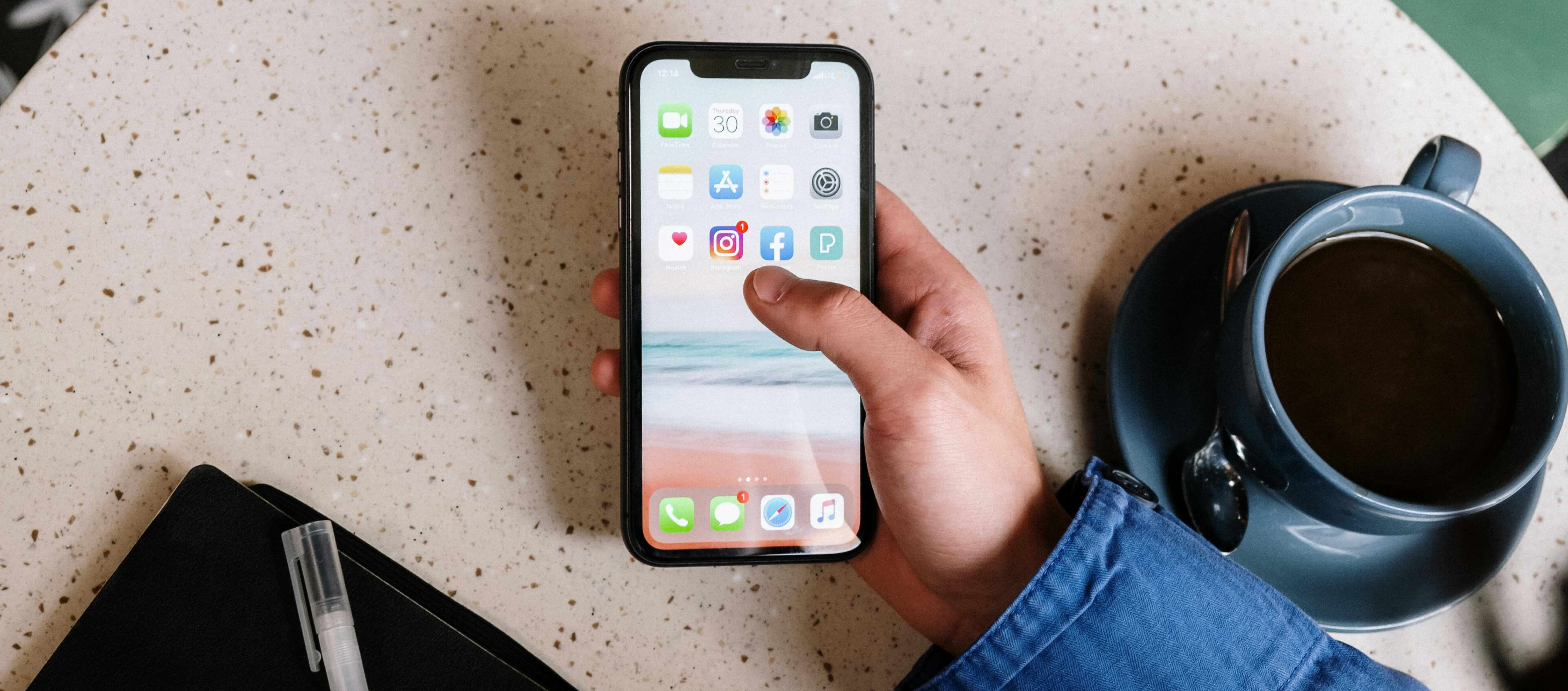 person holding mobile device over table