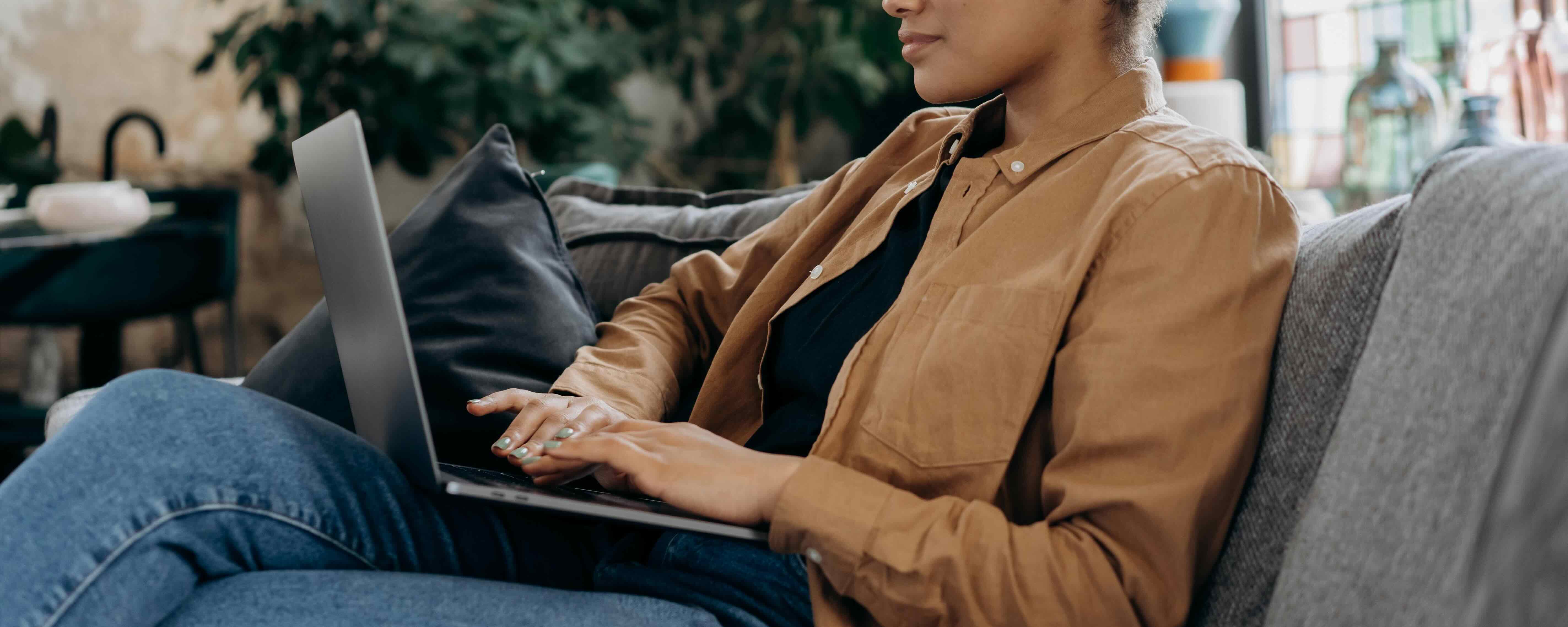 Woman sitting on couch using laptop