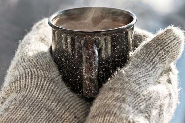 Gloved hands holding a cup of hot chocolate