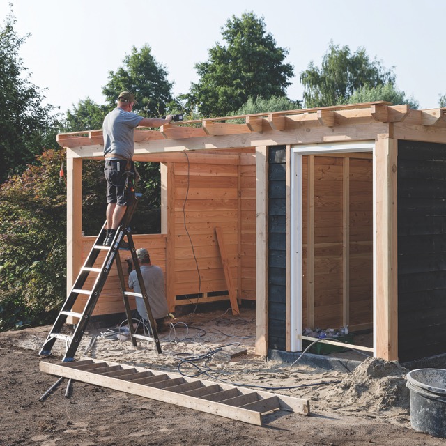 man on a ladder working on a shed