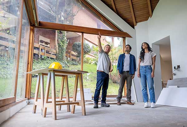 three people standing in new construction pointing to the ceiling