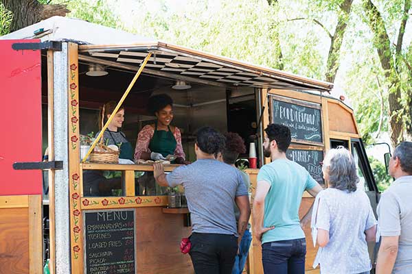 people standing inline and ordering from a food truck