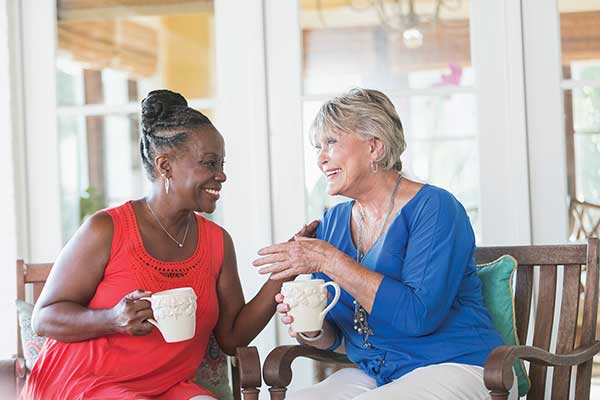 Two women smiling while sharing tea together