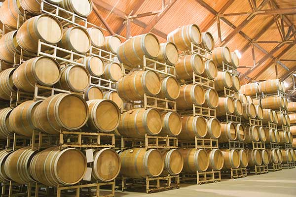 Large stack of wine barrels inside of large storage building