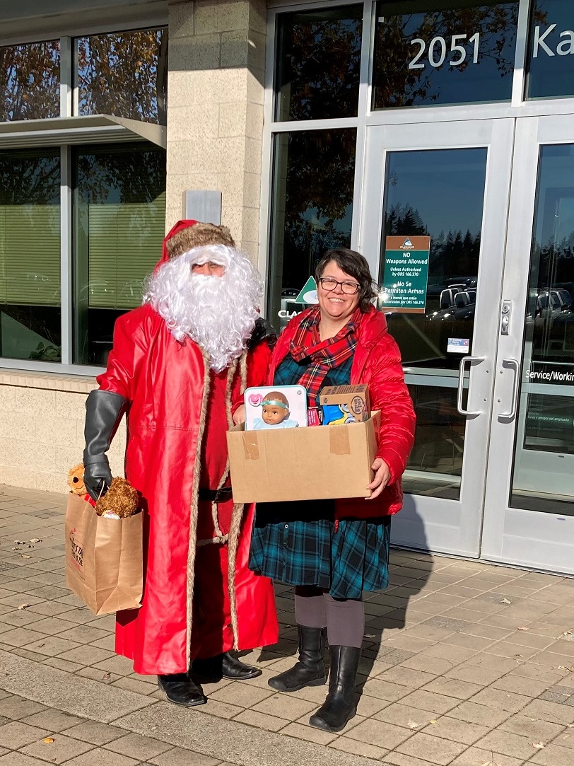Woman holding a box of presents standing next to Santa Clause
