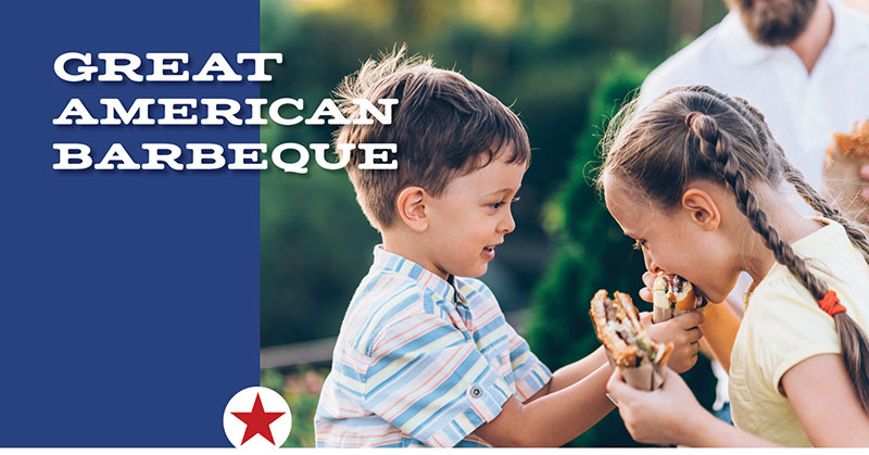 Two children sharing a sandwich at a backyard barbeque