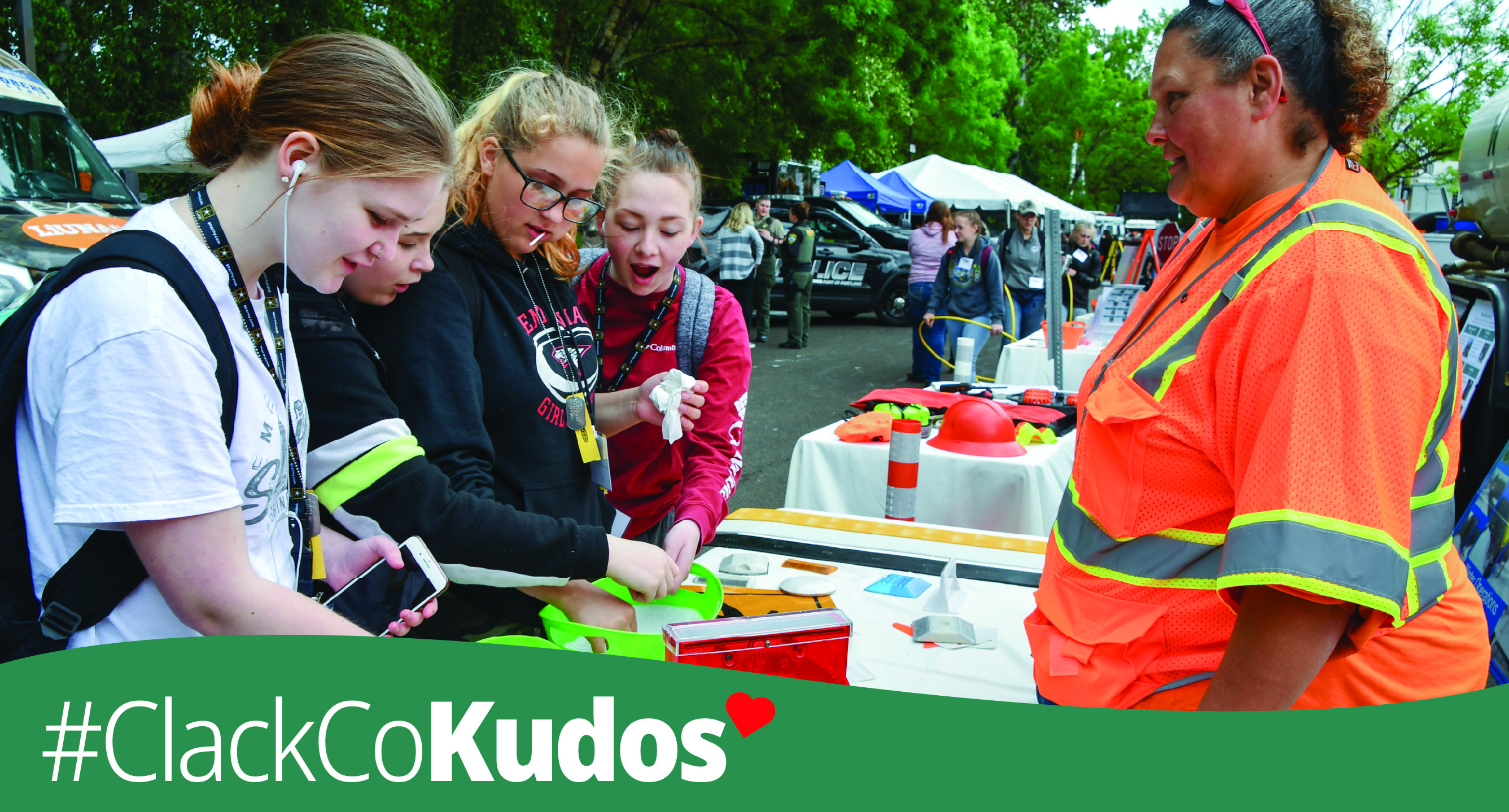 Woman standing at table with young people with #clackCoKudos text across bottom