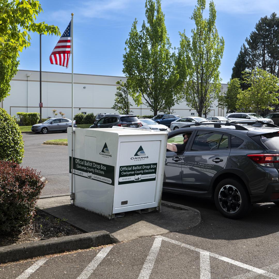 A voter returns his ballot from his car outside the elections office in Oregon City.