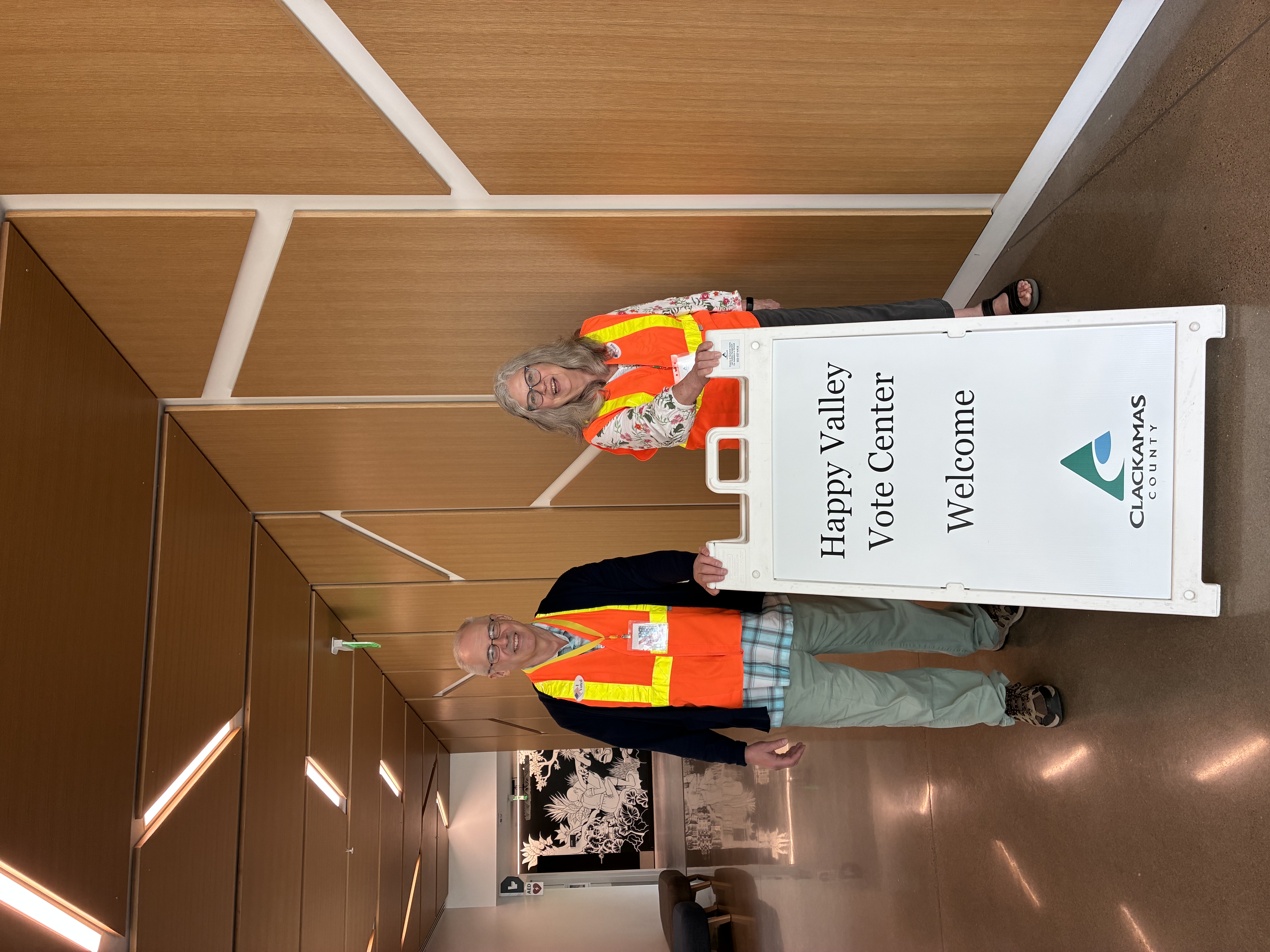 Election staff stand by the Happy Valley Vote Center Welcome sign