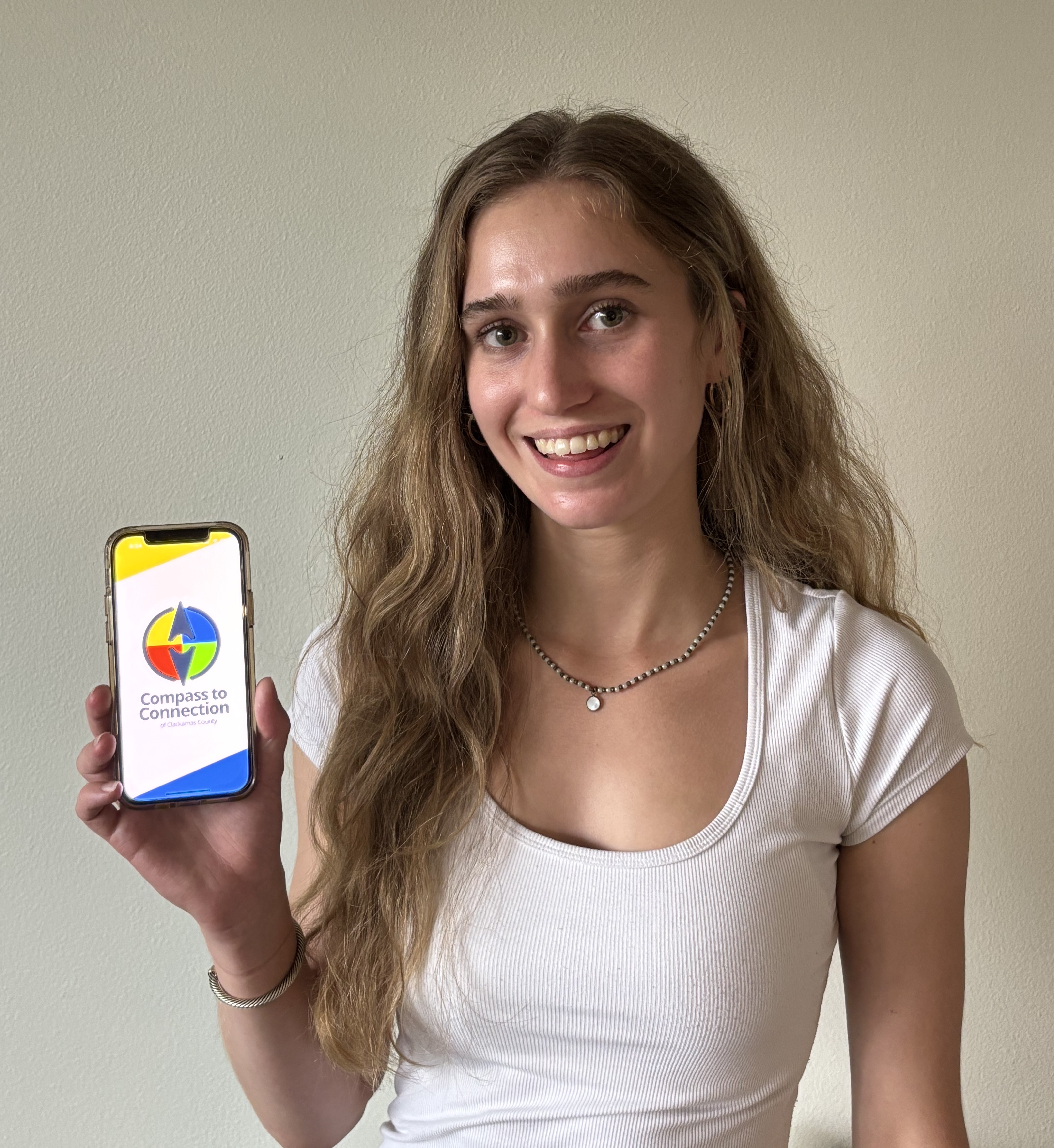 Young woman holding up phone featuring Compass to Connection app