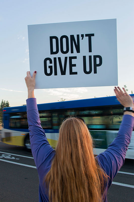 Woman holding up a sign that says Dont give up at a sign rally