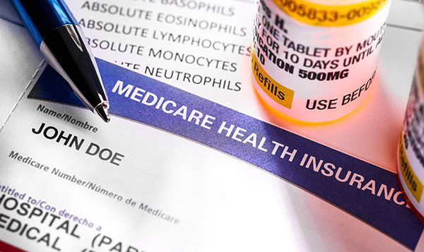 Medicare insurance card next to some bottles of prescription medication