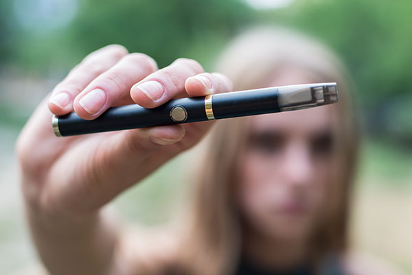Close up of a teenager holding an e-cigarette