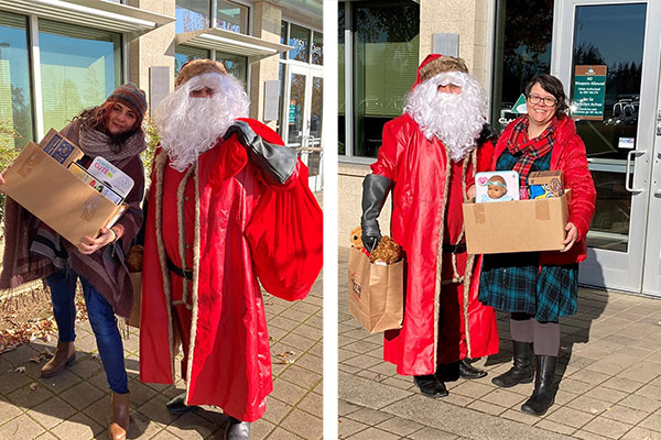 Women holding boxes of presents standing next to Santa Clause