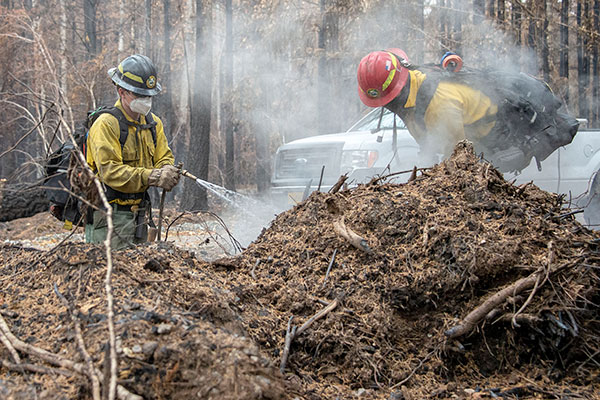 Firefighters with hoses putting out smoldering debris