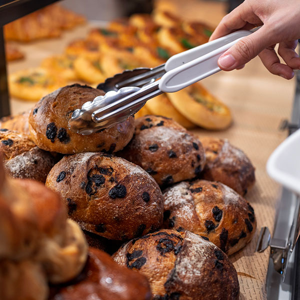 Worker using tongs to serve bread