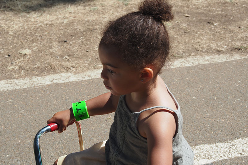 Young girl on a tricycle sporting one our safety bracelets