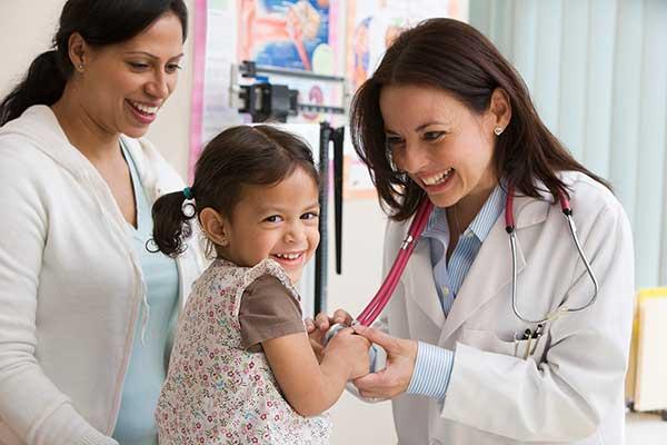 doctor checks heart of little girls while mom is near