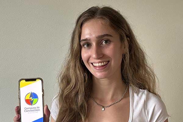 Young woman holding up phone featuring Compass to Connection app