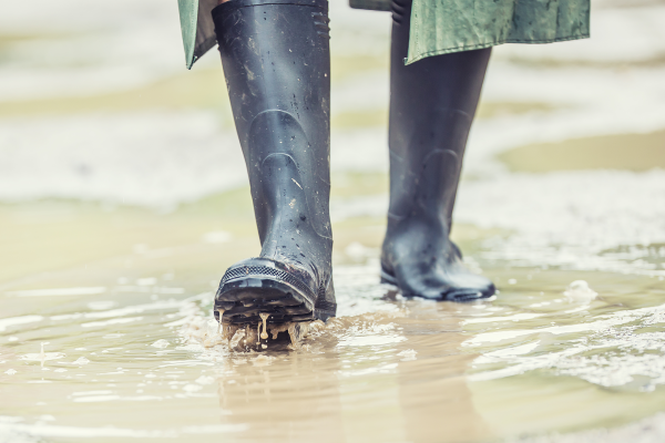 A man with black boots walks on a flooded road