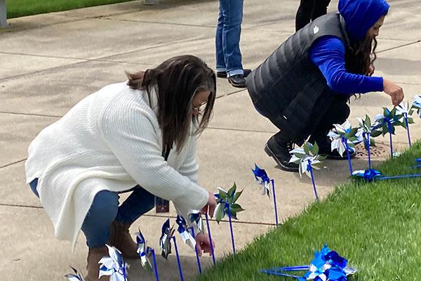 People sticking pinwheels into the grass at the Circle of Honor