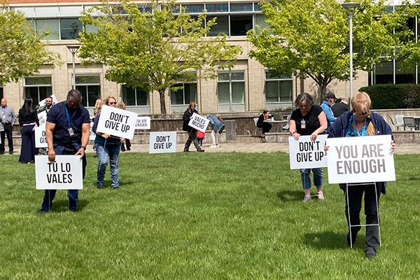 People placing signs with hopeful messages into the grass at the Circle of Honor