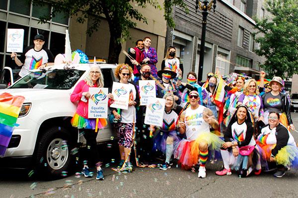 People standing in front of a ClackCo car in the pride parade