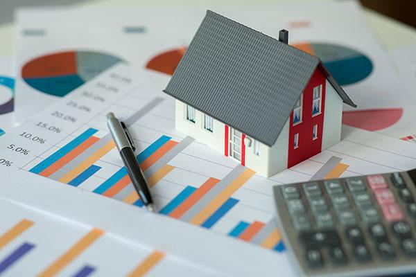 House miniature sitting on a table with a calculator and graphs