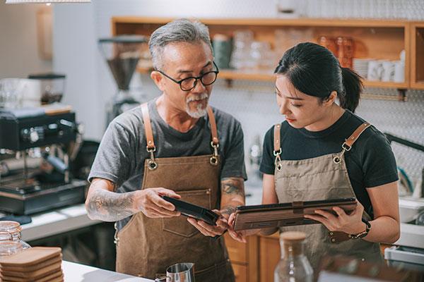 Senior man owner and daughter using digital tablet at bar counter table